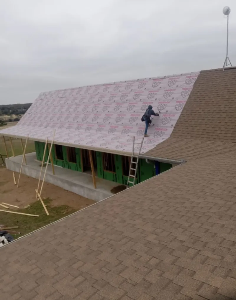 Worker preparing underlayment for a metal roof installation in Wayne